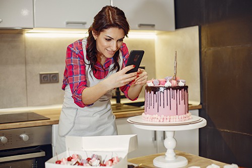 Woman taking a photo of a pink cake she has made