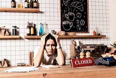 Cafe owner behind her counter stressing over paperwork