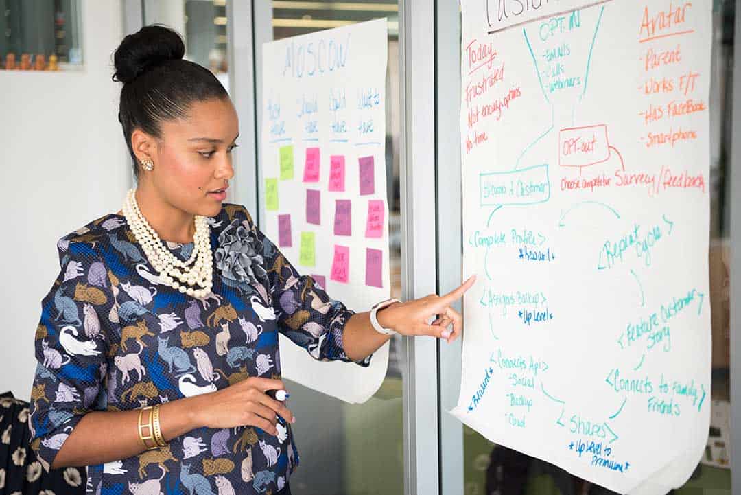 Woman pointing to her presentation on a pinned up piece of paper