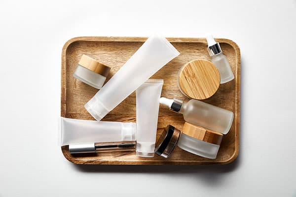 Empty clear cosmetics containers on a wood tray
