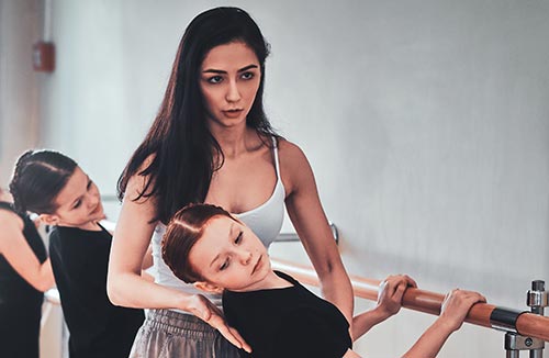 Ballerina teacher with her three young students at the barre