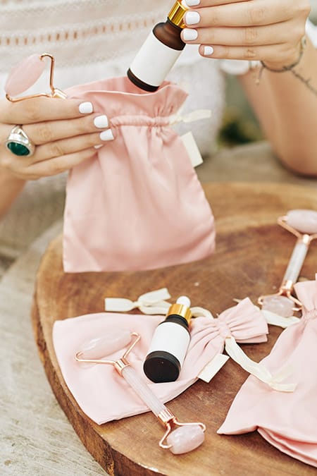 Pink silk bags, quartz face rollers on a wooden table.