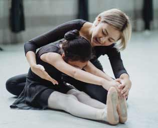 dance instructor helping a student keep posture through a leg stretching exercise before dancing